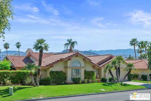 mediterranean / spanish home with a mountain view, a front yard, and a garage