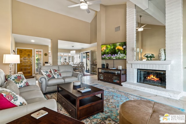 living room featuring ceiling fan, high vaulted ceiling, and a fireplace