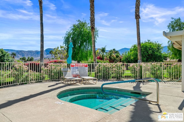 view of swimming pool with a mountain view, a patio area, and a community hot tub