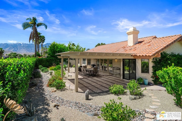 back of property with a mountain view and a patio area