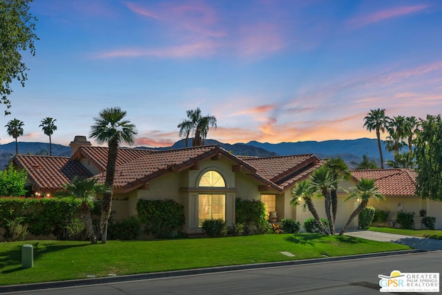 mediterranean / spanish-style home featuring a mountain view, a garage, and a yard