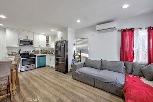 kitchen featuring white cabinets, light hardwood / wood-style floors, stainless steel appliances, and a wall mounted AC