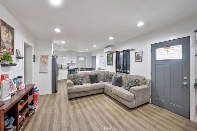 living room with an AC wall unit, sink, and light wood-type flooring