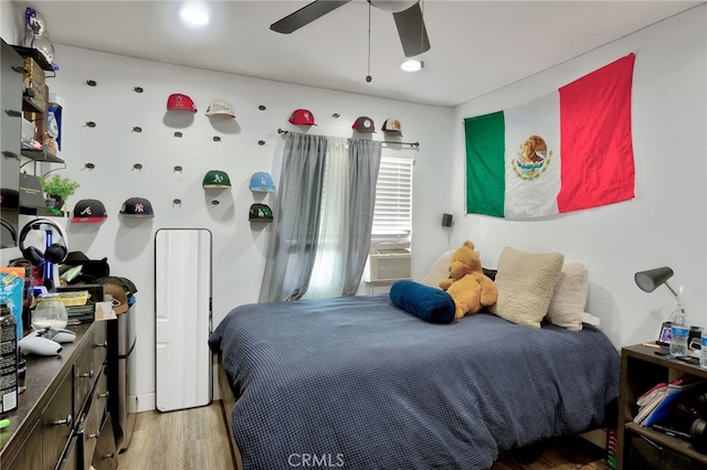 bedroom with ceiling fan, cooling unit, and light wood-type flooring