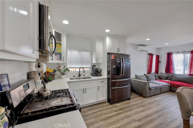 kitchen with white cabinets, stainless steel fridge, sink, and light hardwood / wood-style flooring