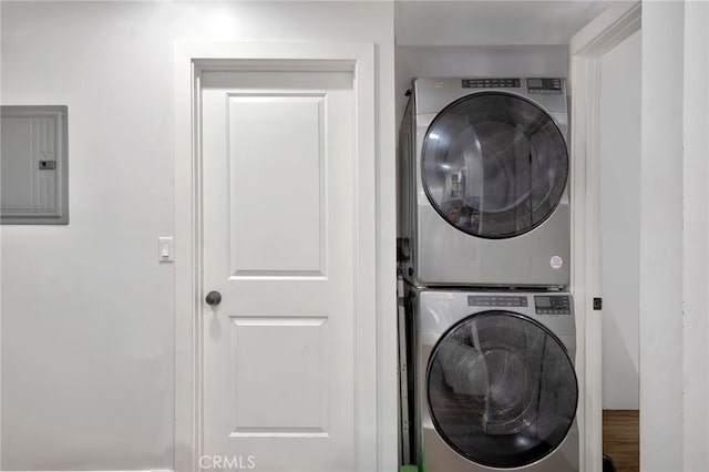 clothes washing area featuring electric panel and stacked washer and clothes dryer