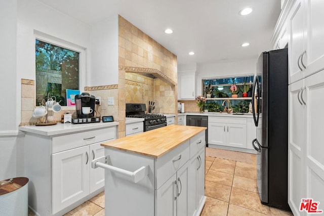 kitchen featuring black appliances, wood counters, white cabinetry, and a kitchen island