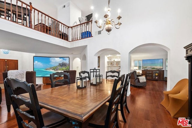 dining room with an inviting chandelier, a towering ceiling, and dark hardwood / wood-style floors