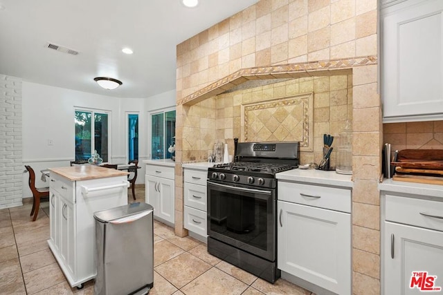 kitchen with gas stove, decorative backsplash, white cabinetry, and light tile patterned floors