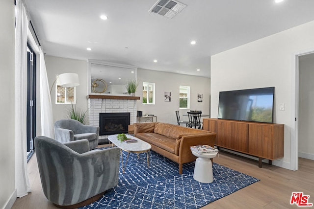 living room with light hardwood / wood-style flooring and a brick fireplace