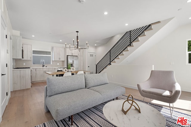 living room featuring light hardwood / wood-style floors, a notable chandelier, and sink