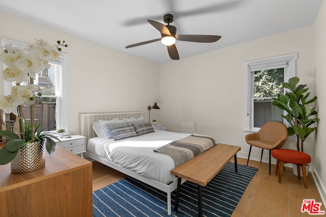 bedroom with ceiling fan, light hardwood / wood-style flooring, and multiple windows