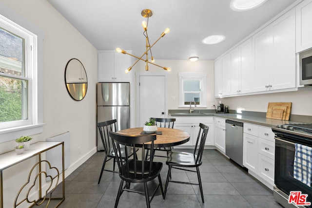 kitchen with dark tile patterned floors, sink, white cabinetry, and stainless steel appliances