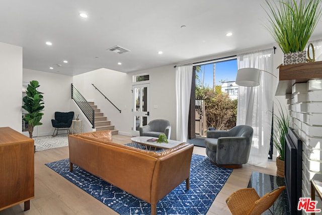 living room featuring a brick fireplace and light wood-type flooring