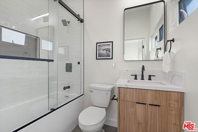 full bathroom featuring vanity, toilet, and shower / bath combination with glass door