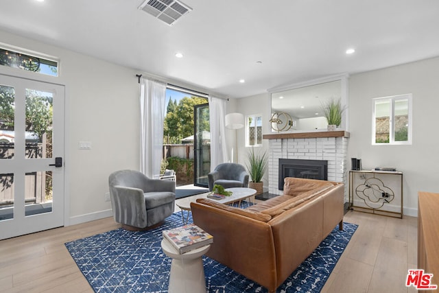 living room with a fireplace, light hardwood / wood-style flooring, and a wealth of natural light