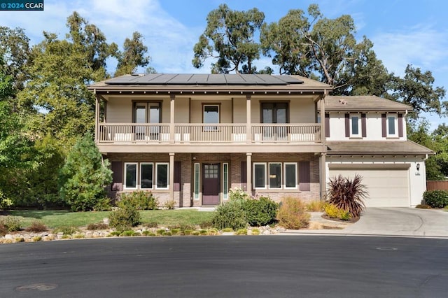 view of front facade featuring solar panels, a balcony, a porch, and a garage