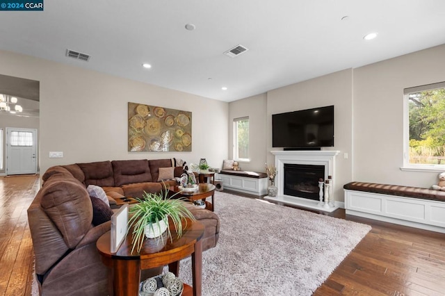 living room with a wealth of natural light, dark hardwood / wood-style flooring, and an inviting chandelier