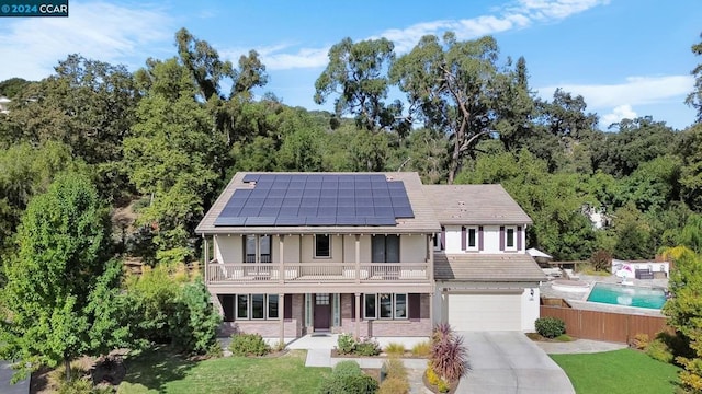 view of front of house featuring solar panels, a garage, a balcony, and a front yard