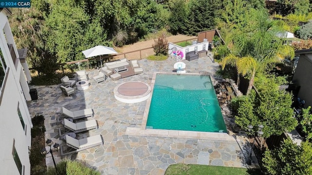 view of swimming pool with an outdoor living space with a fire pit and a patio