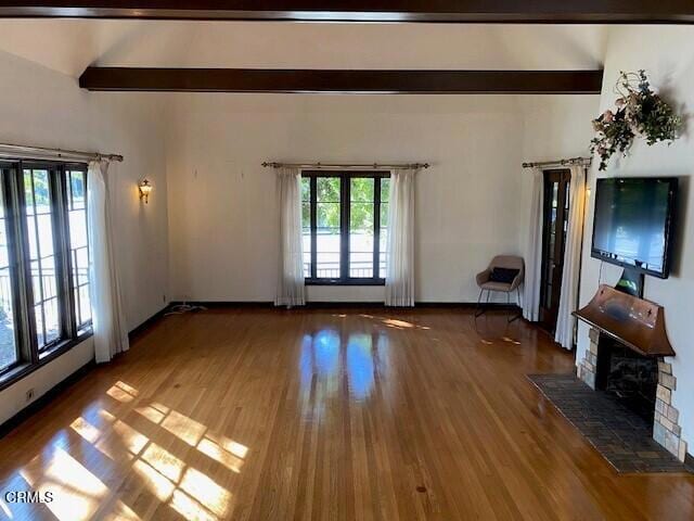 unfurnished living room featuring beamed ceiling, a fireplace, and hardwood / wood-style flooring