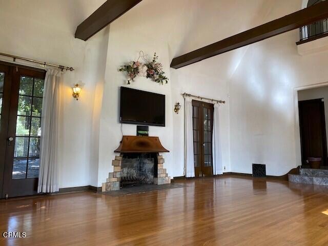 unfurnished living room with beam ceiling, hardwood / wood-style floors, and high vaulted ceiling