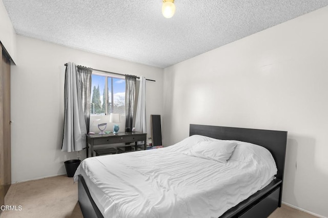 bedroom with a textured ceiling and light colored carpet