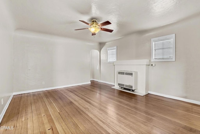 unfurnished living room featuring ceiling fan, heating unit, and hardwood / wood-style flooring