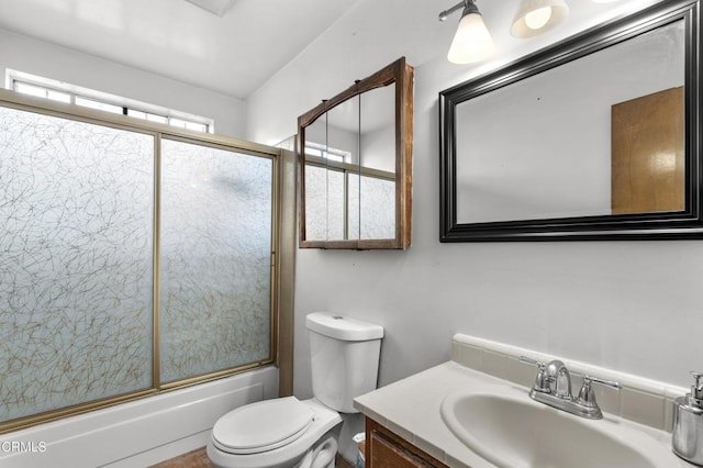 full bathroom featuring toilet, combined bath / shower with glass door, and vanity