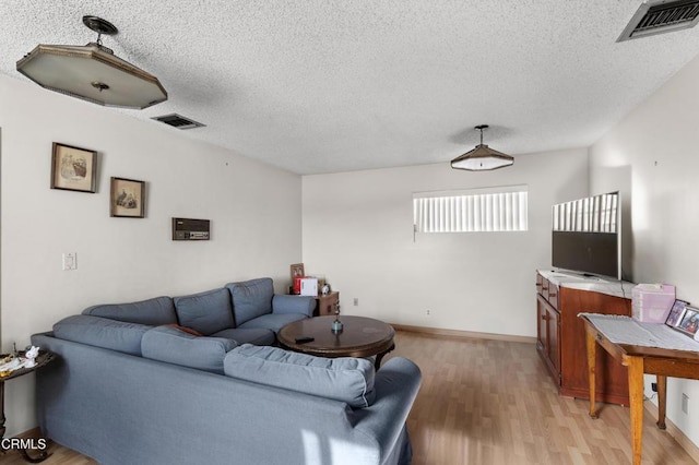 living room with a textured ceiling and light hardwood / wood-style flooring