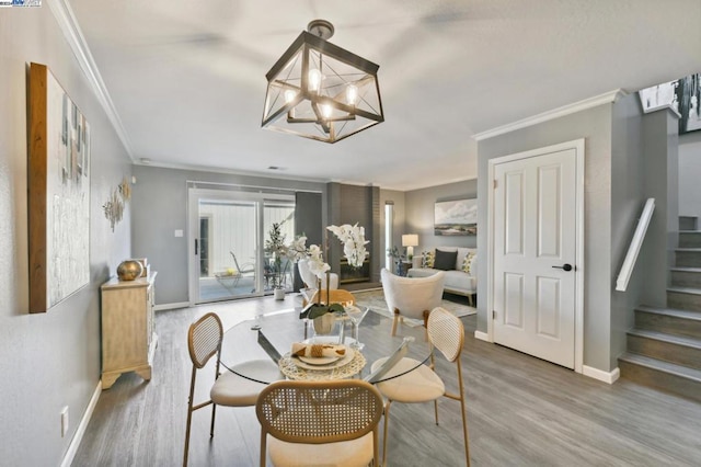 dining space featuring hardwood / wood-style flooring, crown molding, and an inviting chandelier