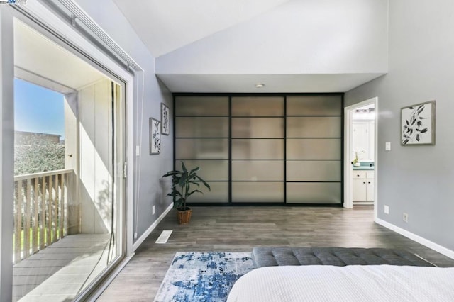 bedroom featuring dark hardwood / wood-style flooring, ensuite bathroom, and lofted ceiling