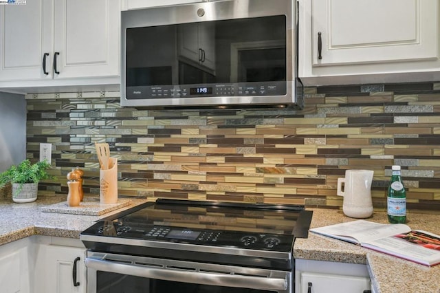 kitchen featuring white cabinets, decorative backsplash, stainless steel appliances, and light stone countertops