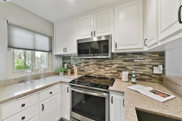 kitchen with white cabinets, backsplash, stainless steel appliances, and light stone counters