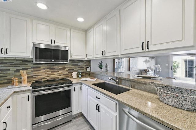 kitchen with white cabinets, decorative backsplash, stainless steel appliances, and sink