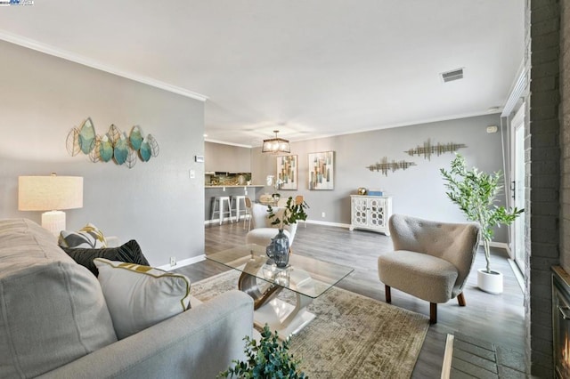 living room with crown molding, a fireplace, and wood-type flooring