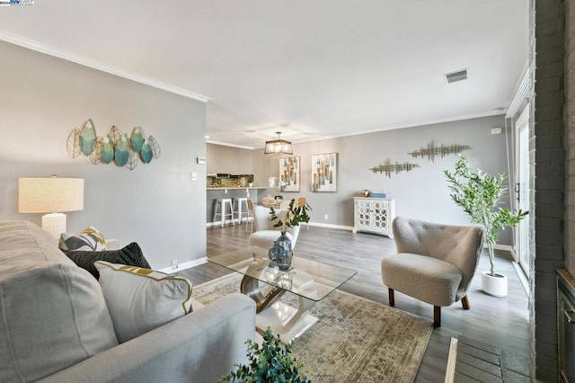 living room with crown molding, wood-type flooring, and a brick fireplace