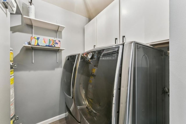 laundry area with cabinets, washer and clothes dryer, and dark wood-type flooring