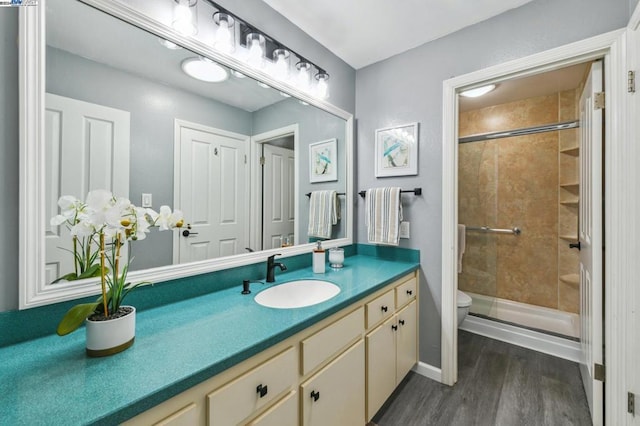 bathroom with wood-type flooring, vanity, toilet, and a shower with shower door