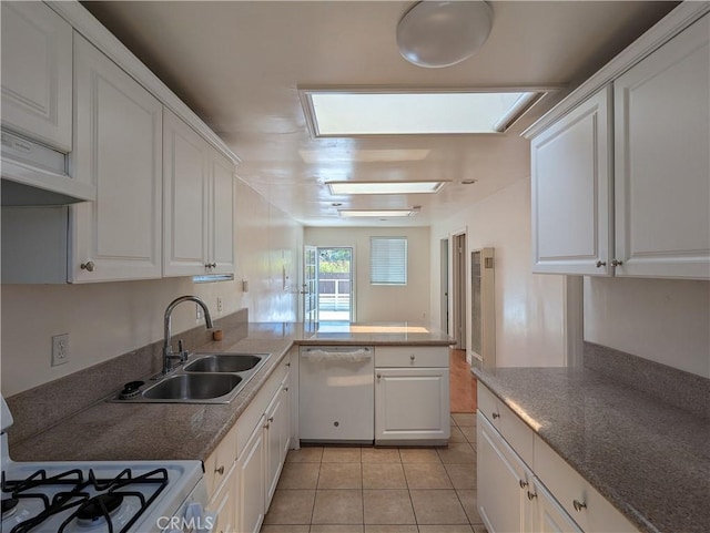 kitchen featuring a skylight, white cabinetry, sink, and white dishwasher