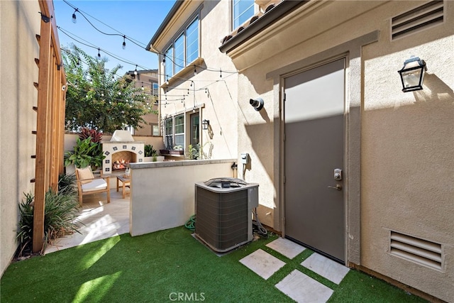 exterior space featuring a patio area, cooling unit, and an outdoor fireplace