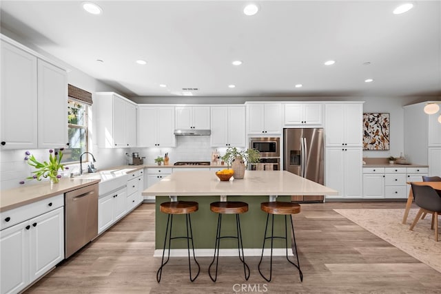 kitchen featuring appliances with stainless steel finishes, white cabinets, a kitchen island, and sink