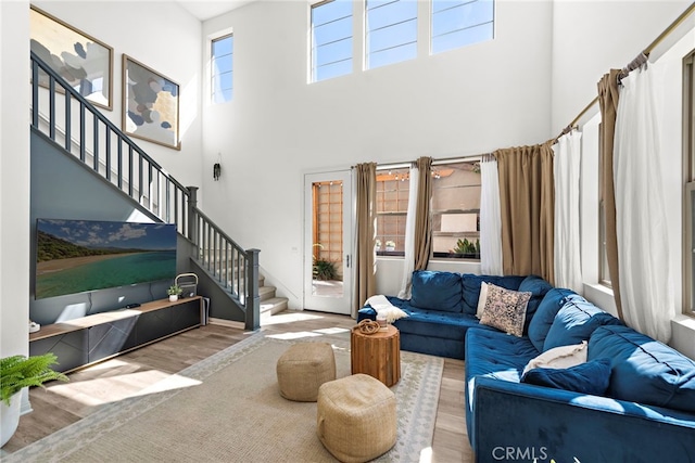 living room with light hardwood / wood-style floors and a towering ceiling