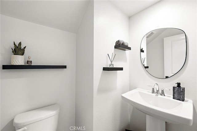 bathroom with toilet, vaulted ceiling, and sink