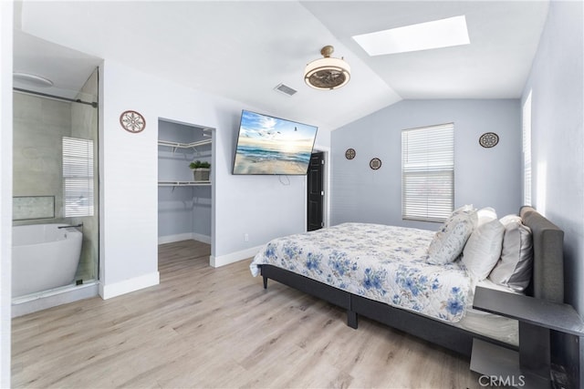 bedroom featuring vaulted ceiling with skylight, light wood-type flooring, a closet, and a spacious closet