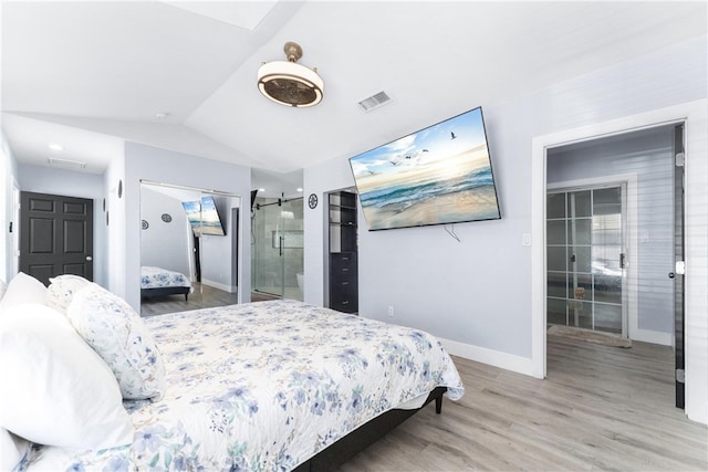 bedroom with vaulted ceiling, ceiling fan, hardwood / wood-style floors, and a barn door