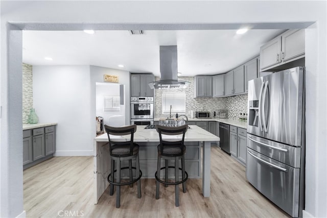 kitchen featuring island range hood, stainless steel appliances, light hardwood / wood-style floors, and a center island