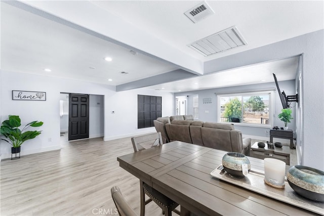 dining room with light hardwood / wood-style floors and beamed ceiling