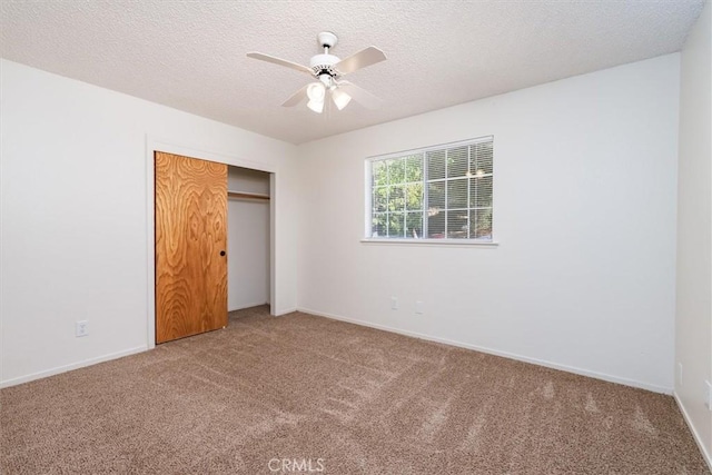 unfurnished bedroom featuring ceiling fan, a closet, carpet, and a textured ceiling