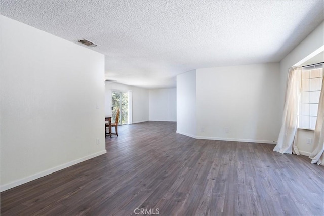 empty room featuring dark hardwood / wood-style flooring and a textured ceiling